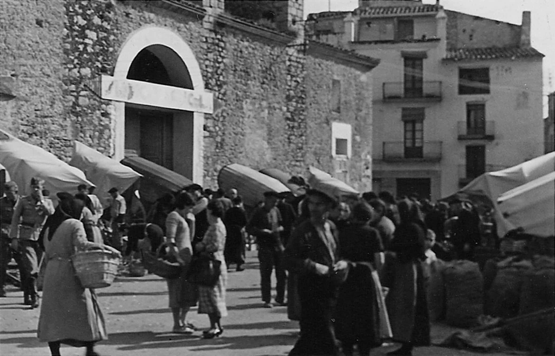 Mercat a la pla&ccedil;a, on s&rsquo;aprecia la porta oberta a la paret lateral durant la Guerra Civil, tapiada posteriorment. Any 1938. Font: Fons &Uacute;rsula Blume - Associaci&oacute; Camp d&rsquo;Aviaci&oacute; de la S&eacute;nia.